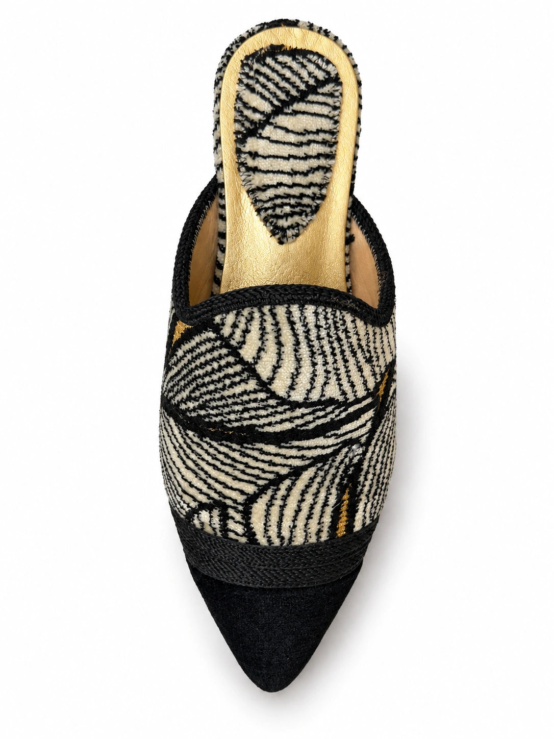 Black and cream leaf-pattern babouche with black pointed toe, braided front band and gold-tone footbed, shown on white.