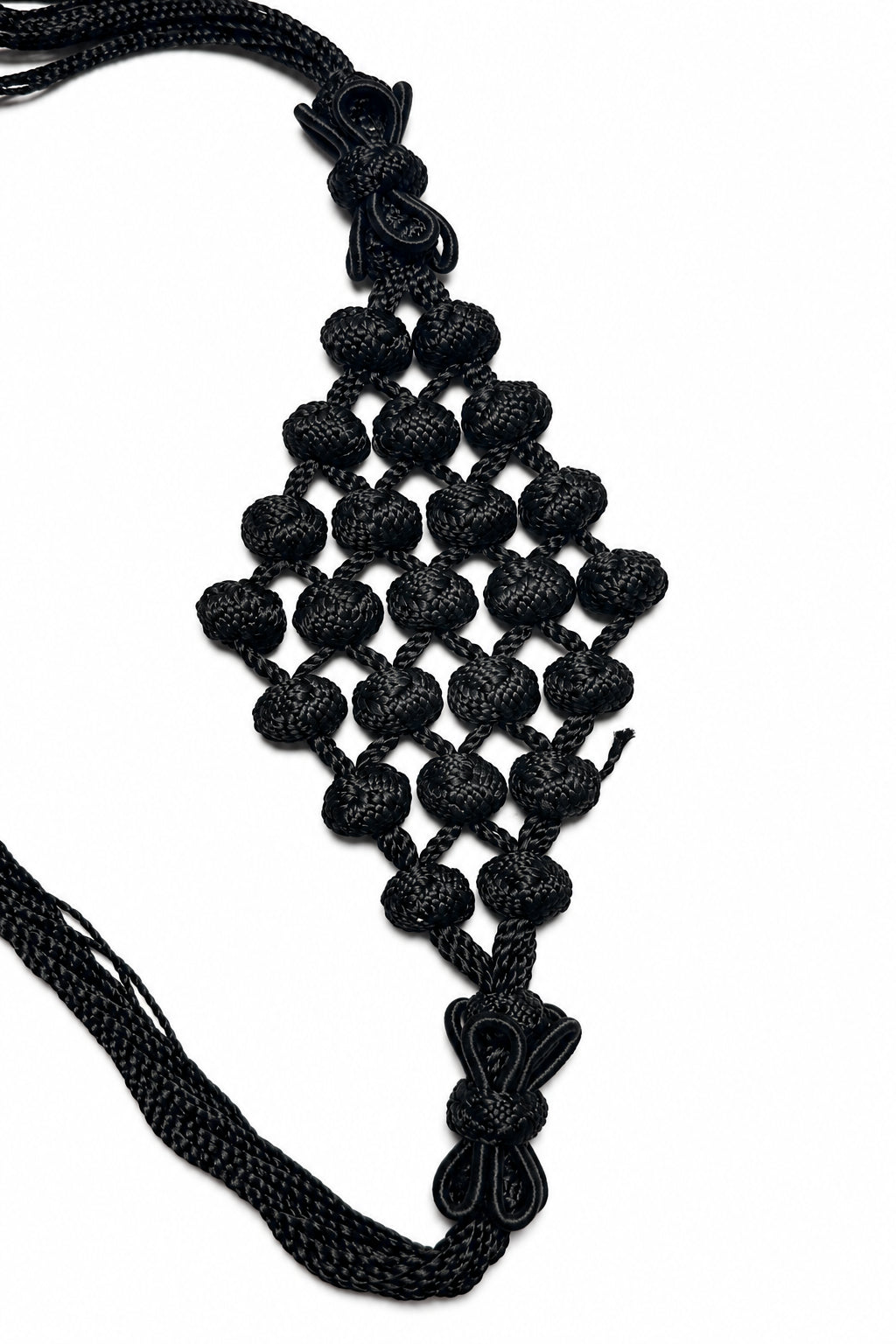 Black cord belt with a diamond-shaped panel of rounded knots and looped end accents, detail view.