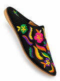 Black babouche with vivid pink, green, yellow, orange and purple embroidered flowers and leaves, shown on white.