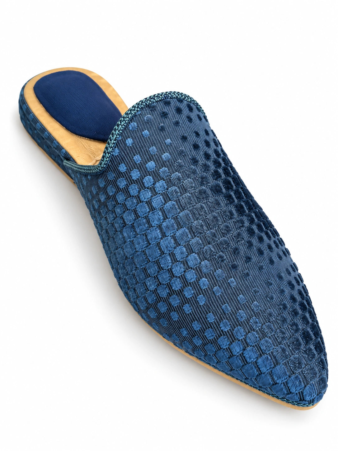 Blue babouche with raised square and dot textures, tonal braided trim and a gold-tone heel rim on white.