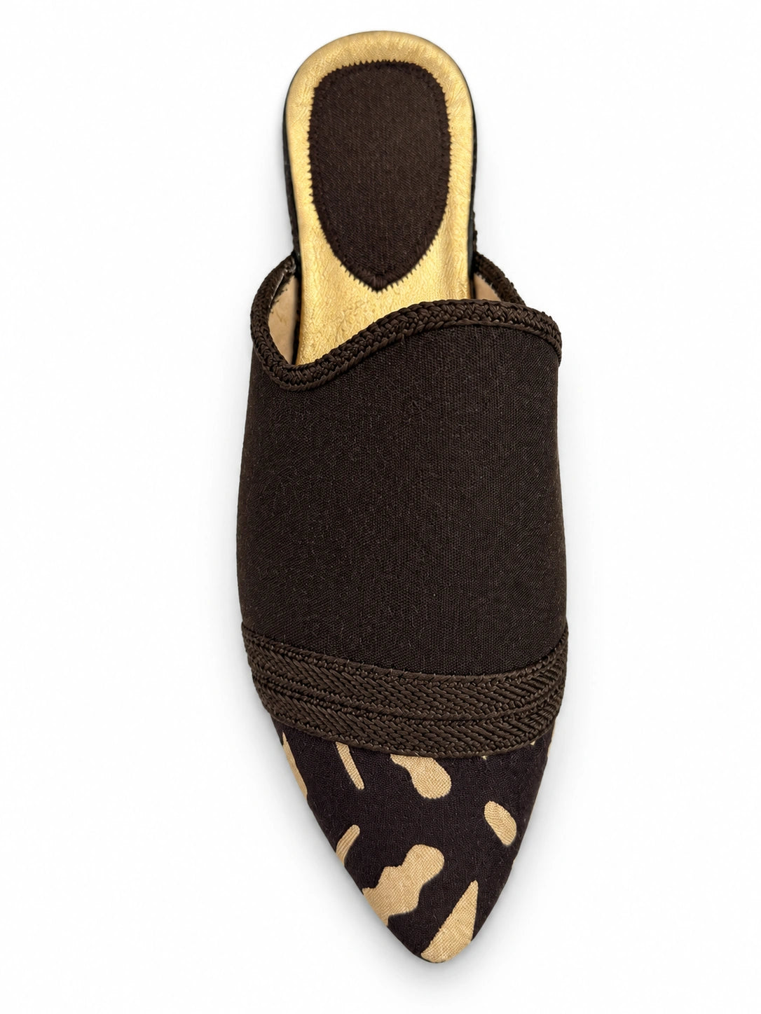 Dark brown babouche with beige spots at the pointed toe and a tonal braided band on a white background.
