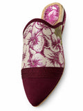Burgundy babouche with an ivory and magenta floral upper, braided band and plain pointed toe on a white background.