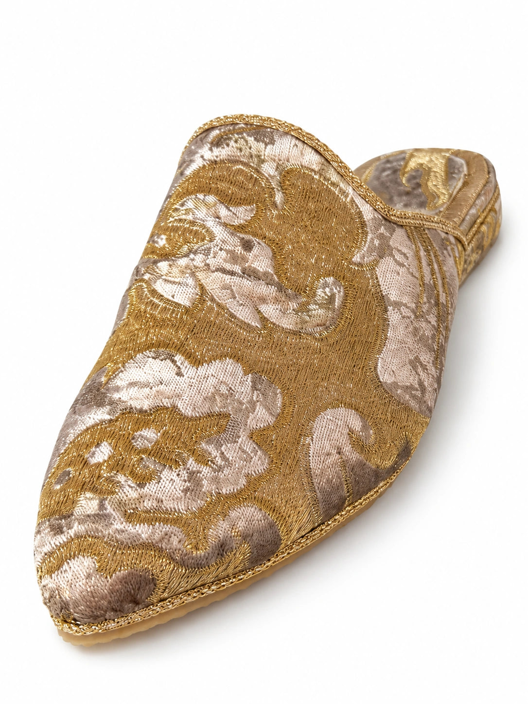 Gold and ivory babouche with large scrolling floral motifs, metallic braided edging and a patterned heel on white.