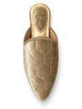 Gold-tone babouche with subtle geometric texture, braided edging and a pointed toe, shown on white.