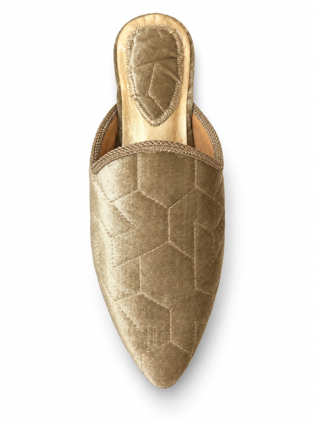 Gold-tone babouche with subtle geometric texture, braided edging and a pointed toe, shown on white.