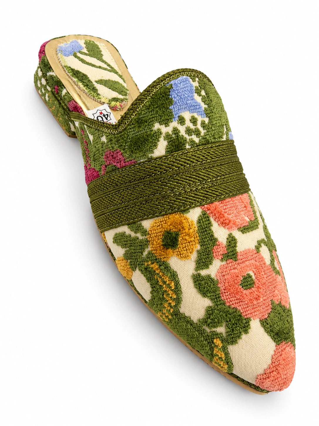 Cream babouche with green leaves, pink flowers and an olive braided band on a white background.