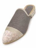 Grey babouche with a pale patterned pointed toe, light metallic braided band and open back on a white background.