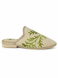 Ivory babouches with green branching leaf motifs across a finely textured upper, on a white background.
