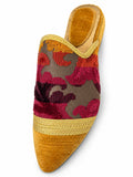 Mustard babouche with a pink and orange floral upper and gold-tone braided band on a white background.