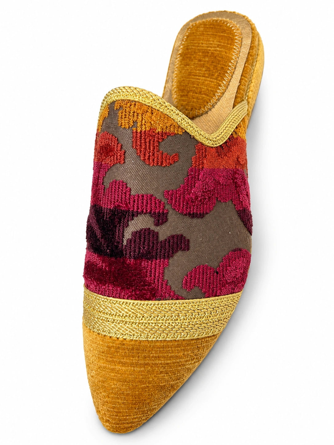 Mustard babouche with a pink and orange floral upper and gold-tone braided band on a white background.