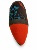 Orange and dark brown babouche with turquoise floral motifs and a dark braided band on a white background.