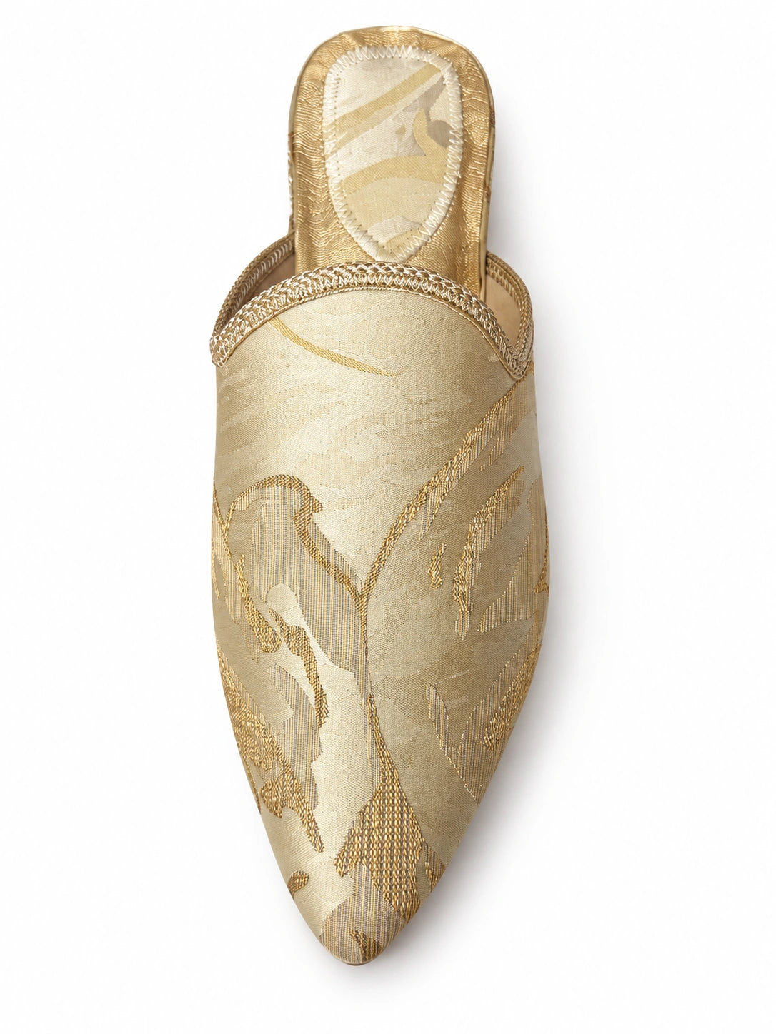 Pale gold floral-pattern babouche with gold-tone braided edging and a pointed toe, shown on white.