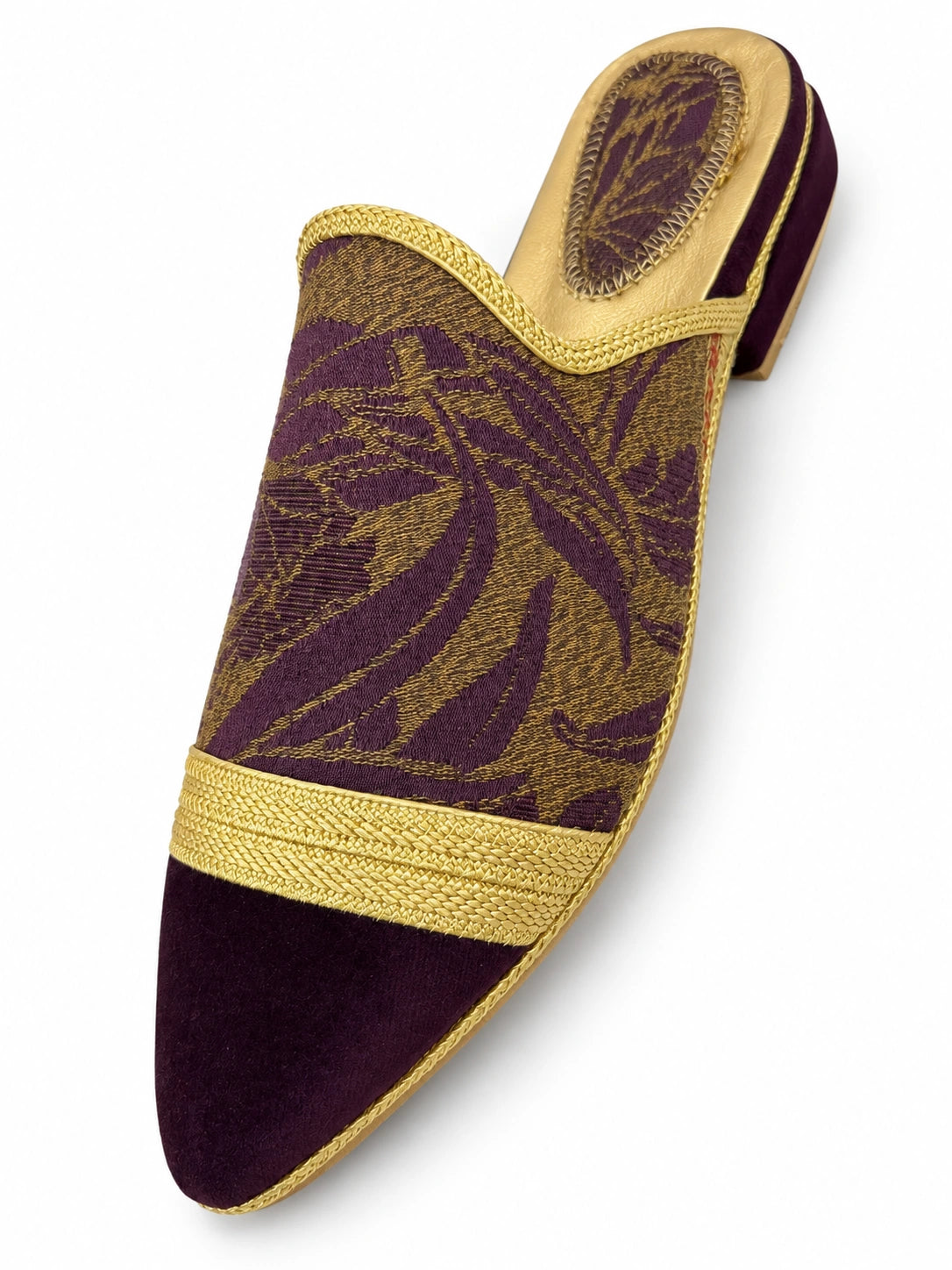 Purple and gold-tone leaf-pattern babouche with gold braided trim and a plain plum pointed toe, shown on white.