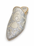Silver and ivory floral pointed-toe babouche with gold-tone edging on a white background.